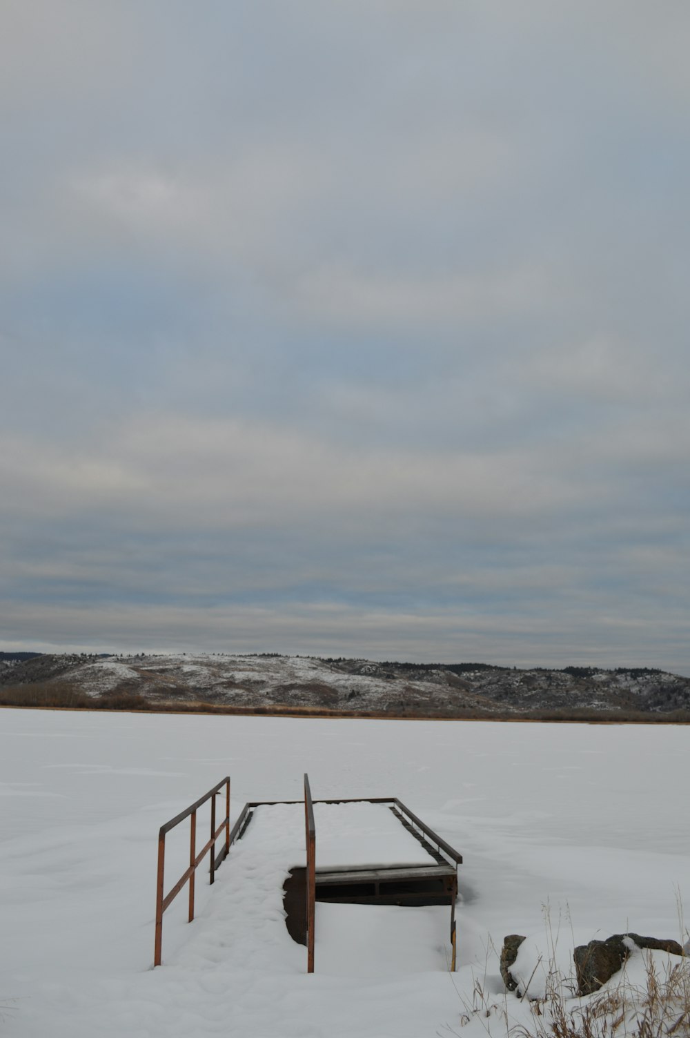 a snow covered field with a wooden structure in the middle of it