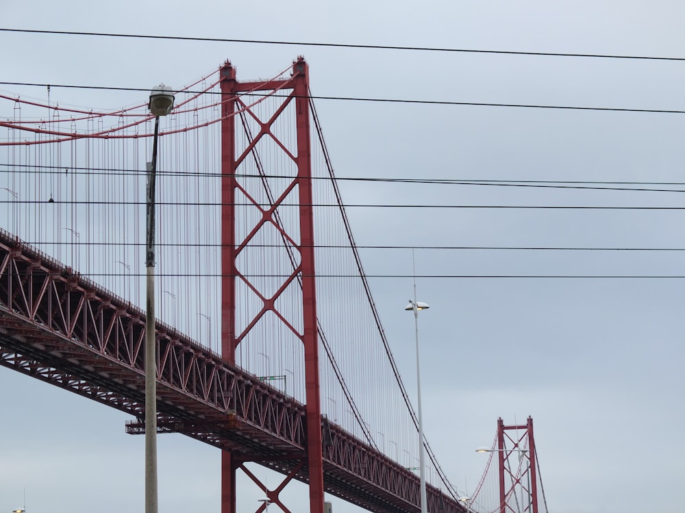 a red bridge with wires above it on a cloudy day