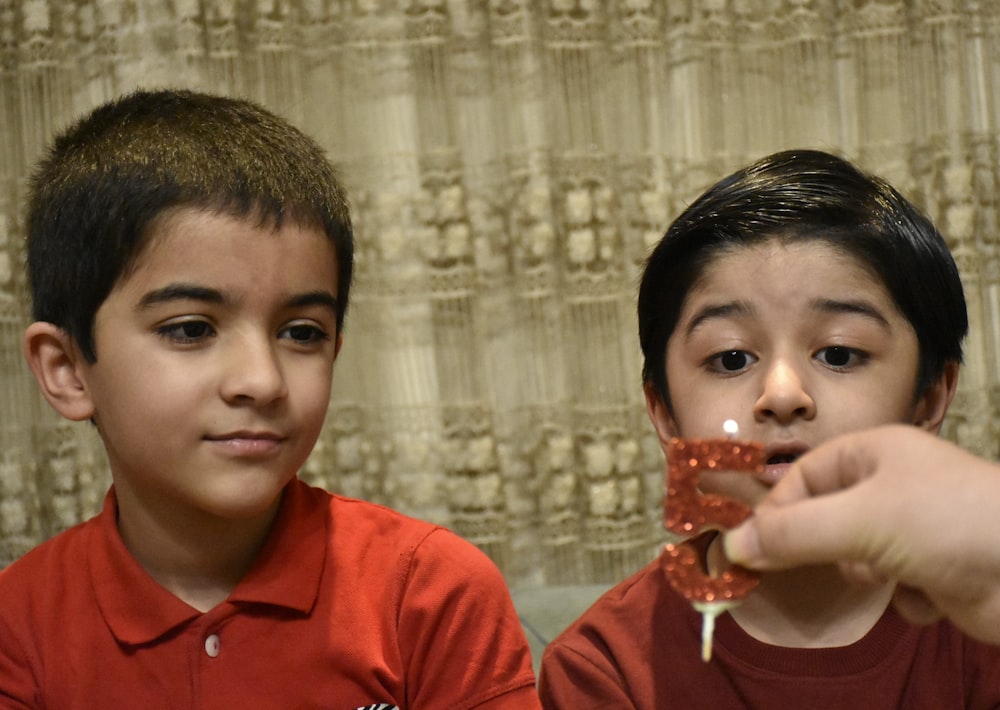 two young boys holding up a piece of cake