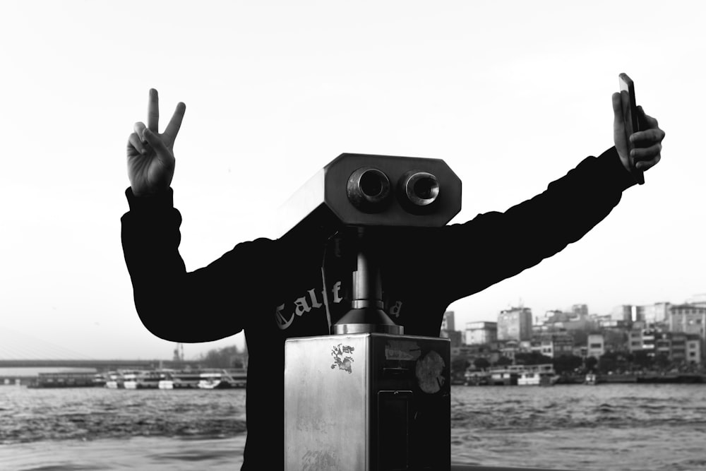 a man standing next to a camera on top of a body of water