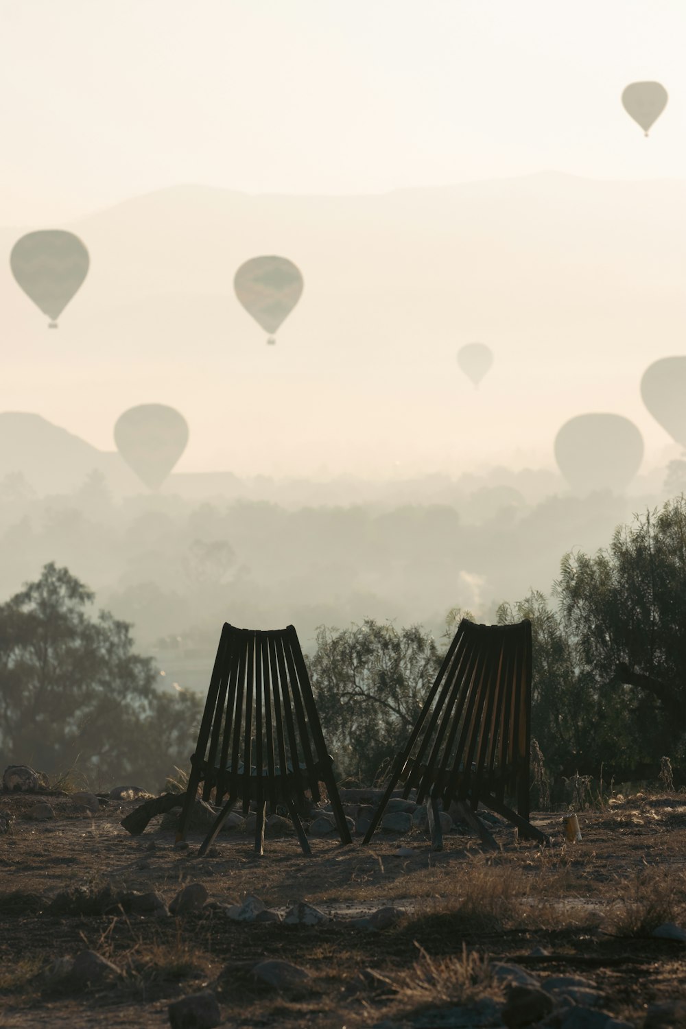 a couple of wooden chairs sitting on top of a field