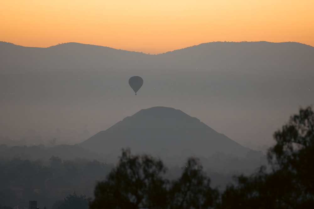 a hot air balloon flying over a mountain range