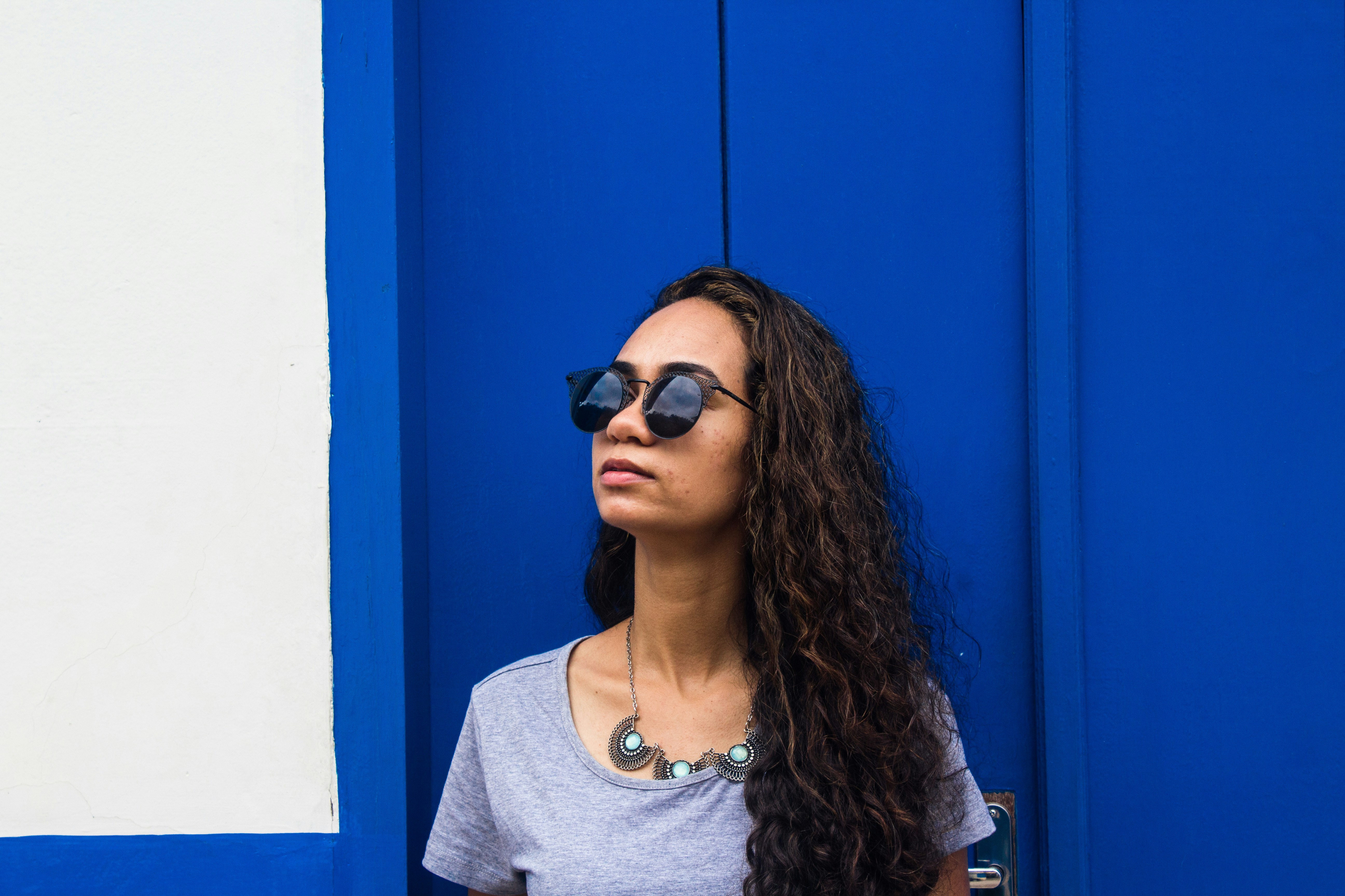 a woman wearing sunglasses standing in front of a blue wall