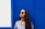 a woman wearing sunglasses standing in front of a blue wall