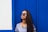 a woman wearing sunglasses standing in front of a blue wall