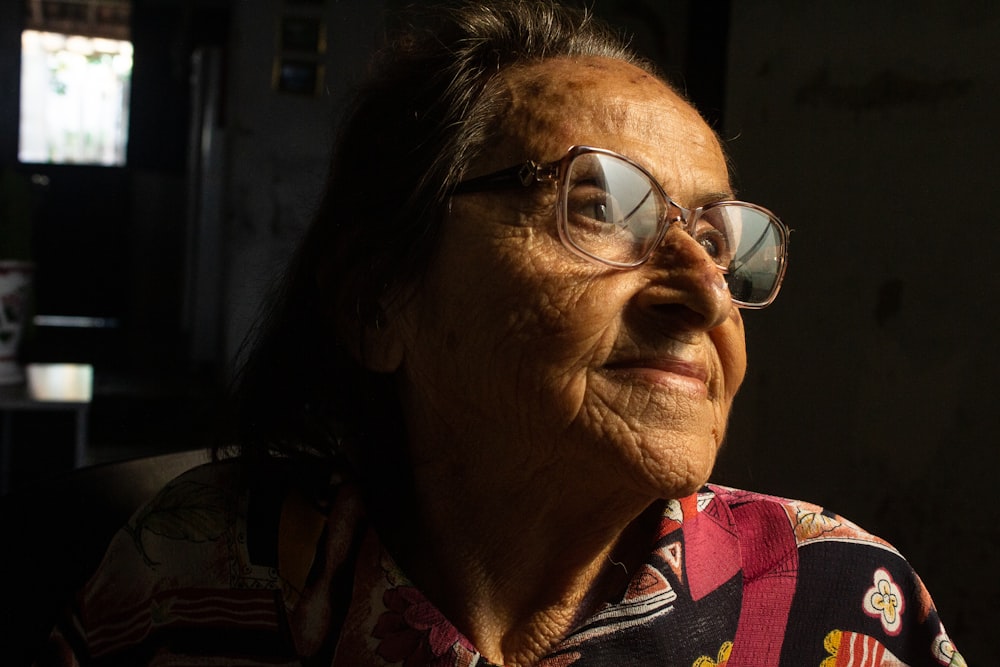 an older woman wearing glasses looking off into the distance