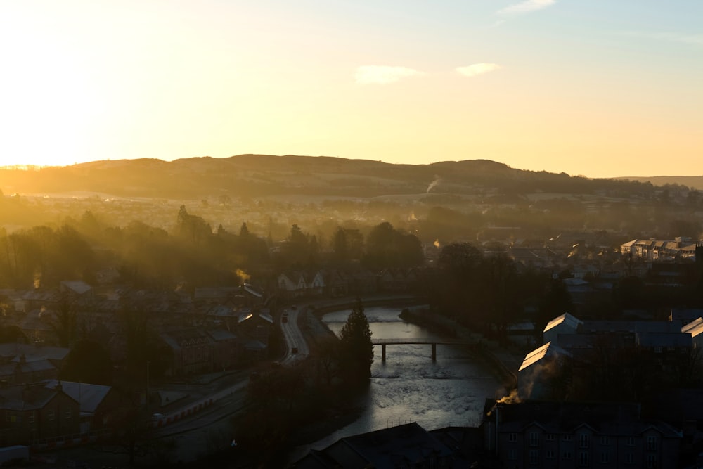 the sun is setting over a city with a river running through it