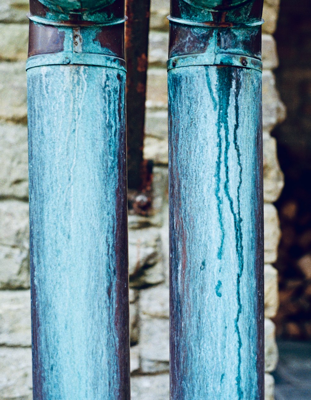 a close up of two metal pipes near a brick wall