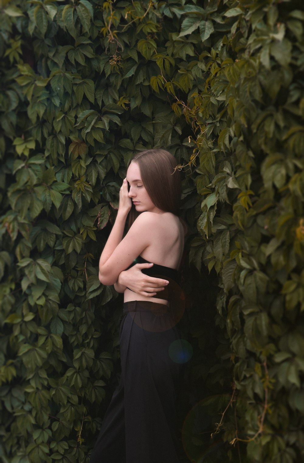 a woman standing in front of a green wall talking on a cell phone