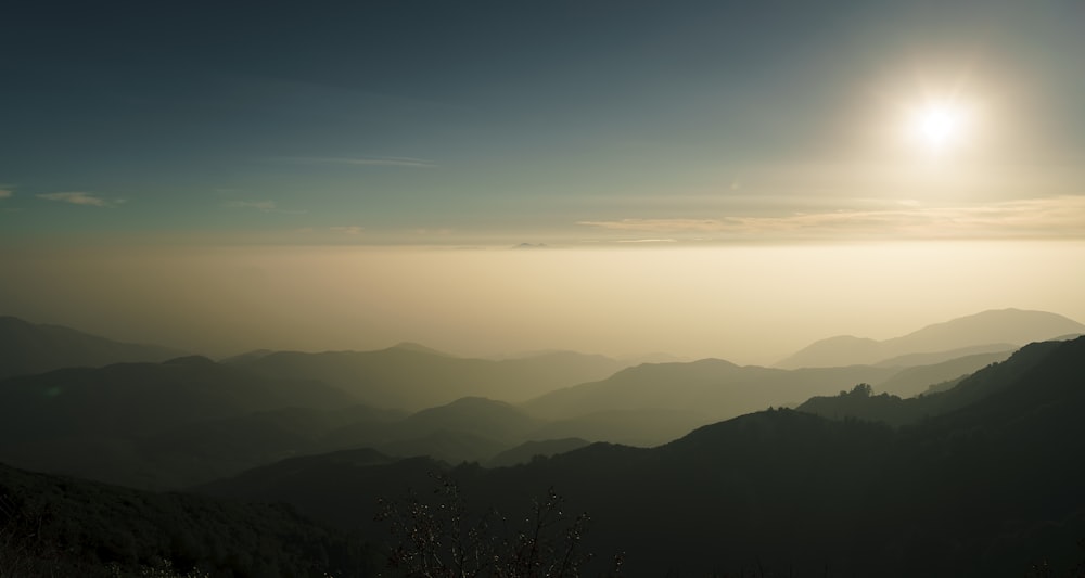 the sun is shining over the mountains in the distance