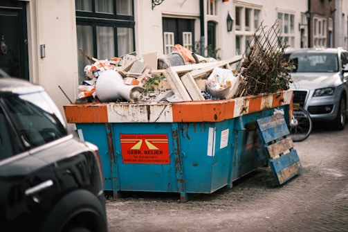a blue dumpster filled with lots of trash on the side of a road