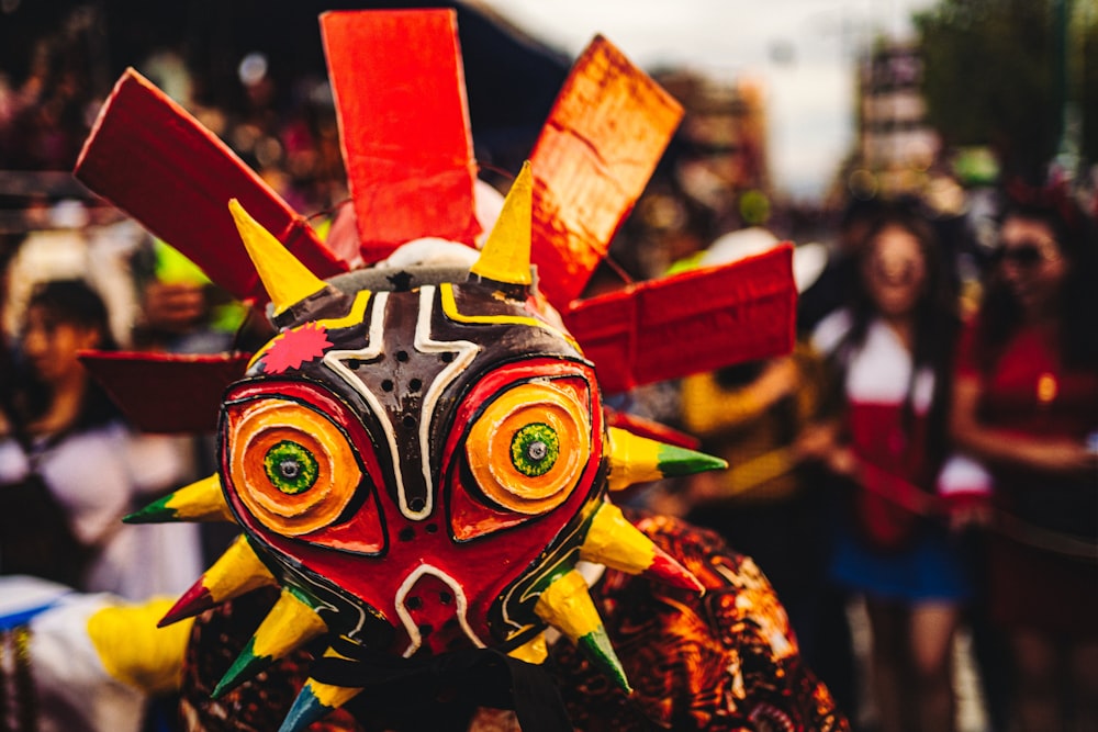 a group of people standing around a colorful mask