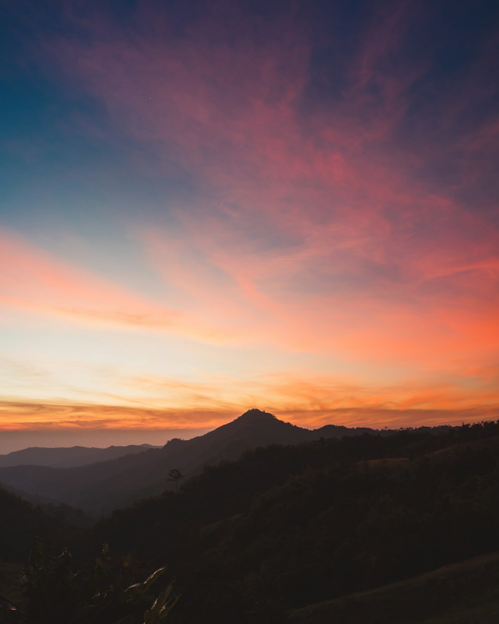 the sun is setting over a mountain range