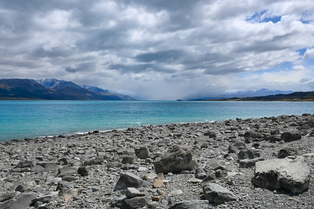 Une plage rocheuse avec de l’eau bleue et des montagnes en arrière-plan