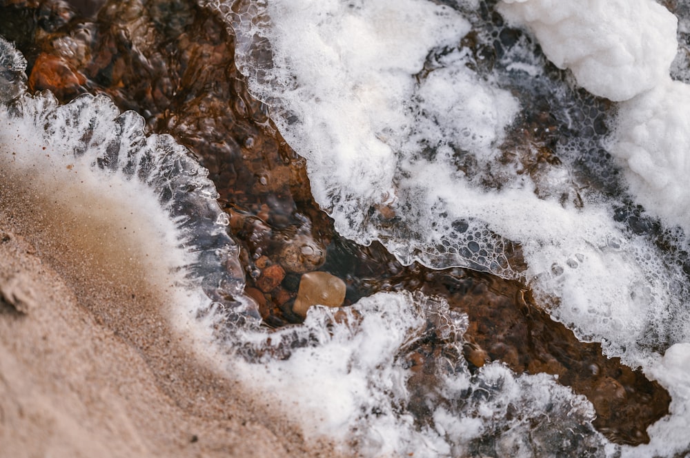 a close up of water and ice on a beach