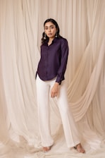Woman in dark purple shirt and white pants