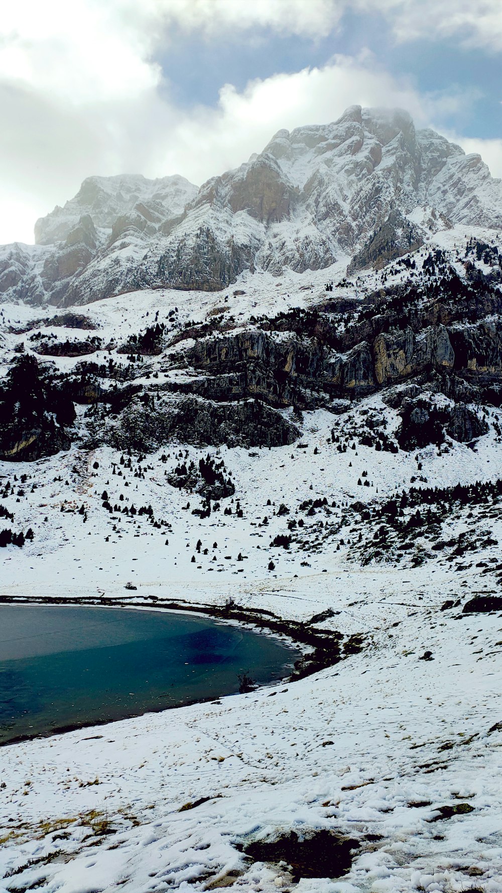 a snow covered mountain with a lake in the foreground