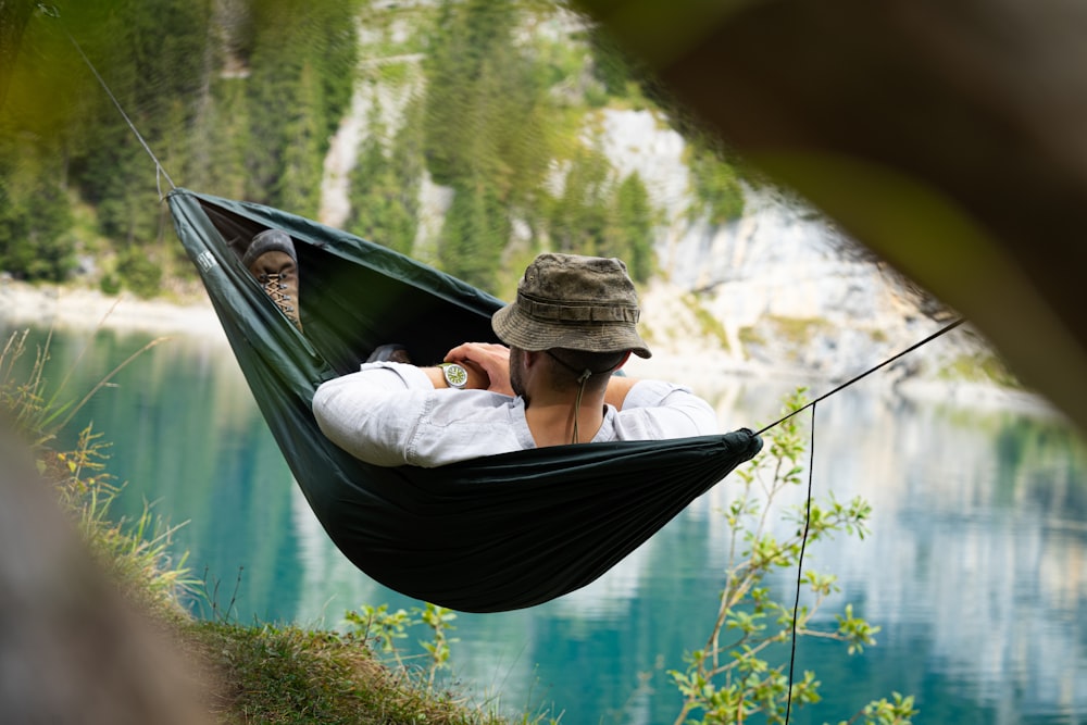 a man sitting in a hammock with a view of a lake