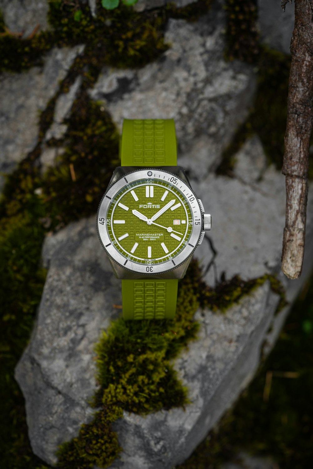 a green watch sitting on top of a rock