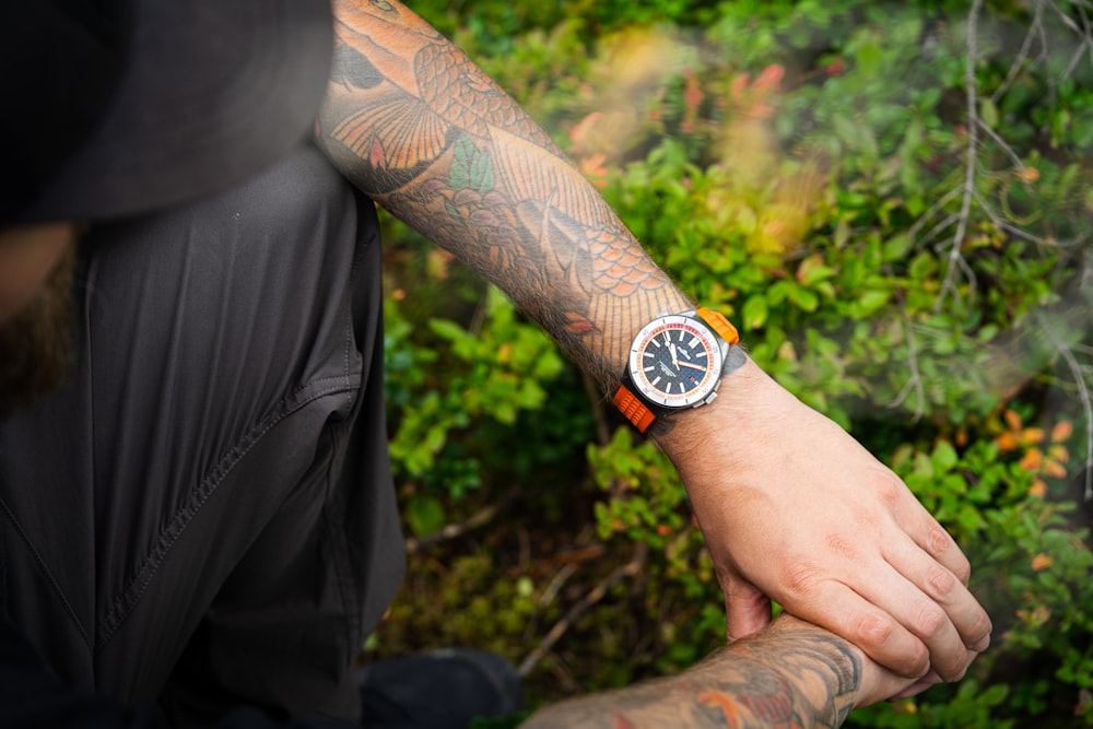 a man with a tattoo on his arm holding a watch
