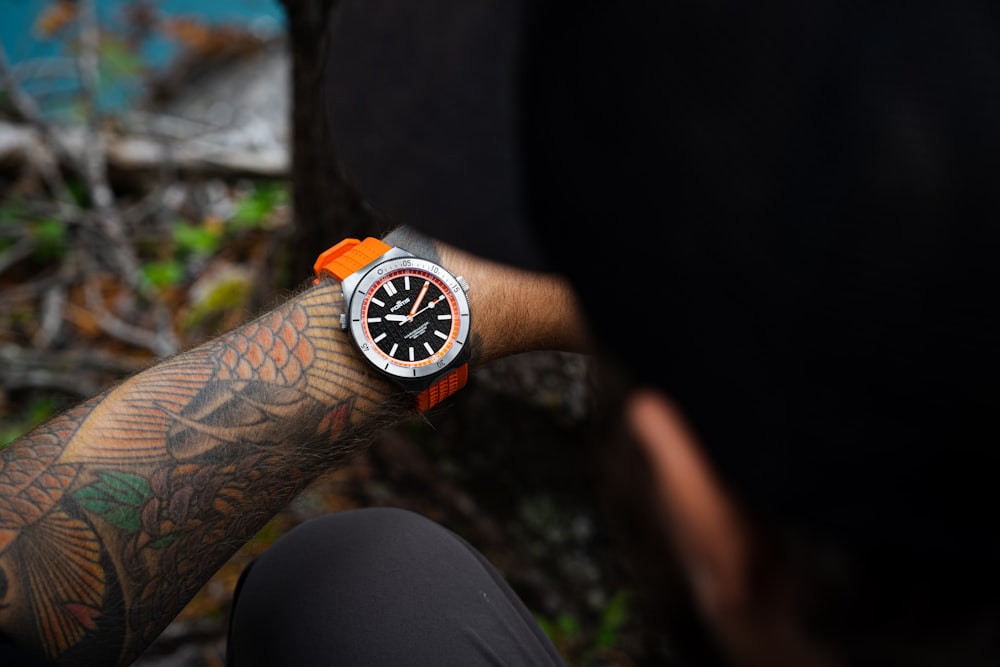 a man with a tattoo on his arm holding a watch