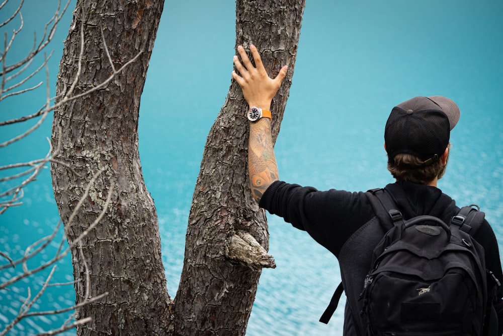 a person reaching up to a tree with a watch on it