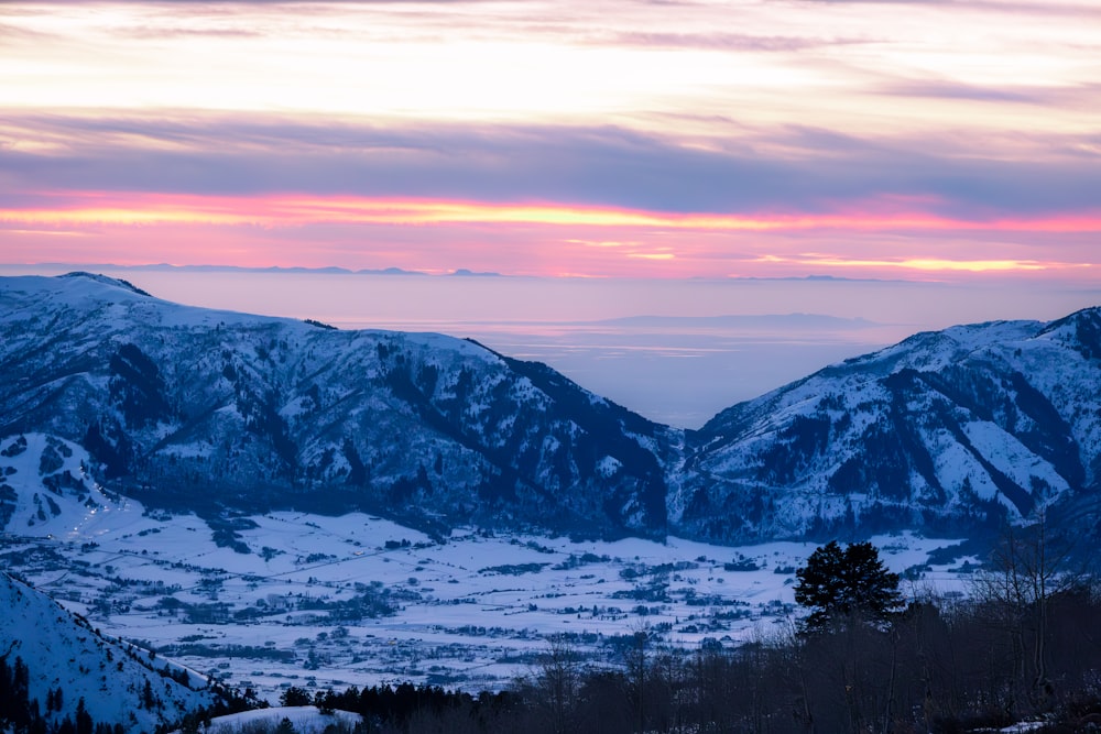 a view of a snowy mountain range at sunset