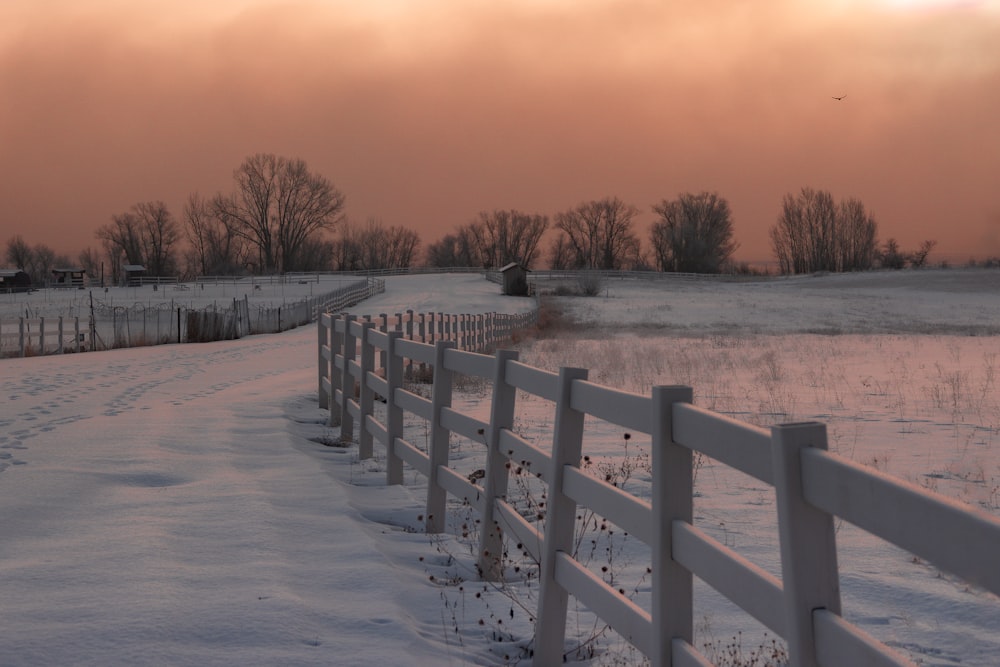 a snow covered field with a white fence