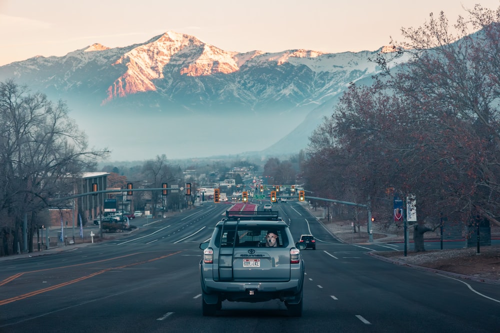 a car driving down a street with mountains in the background