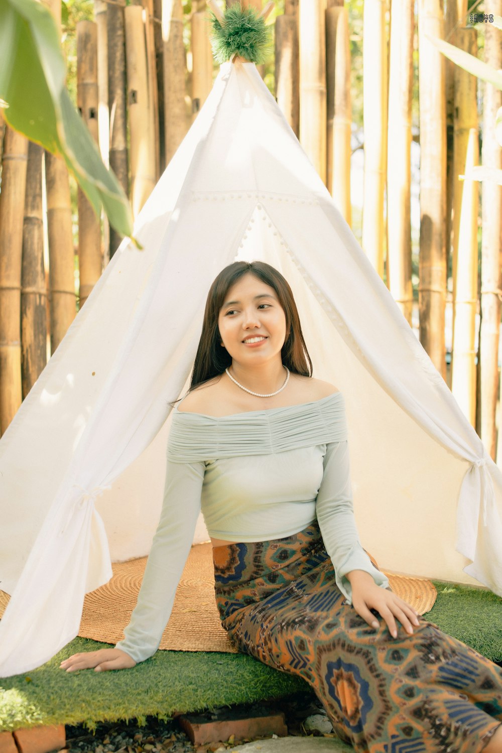 a woman sitting on the ground in front of a teepee