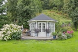 a white gazebo surrounded by flowers and greenery