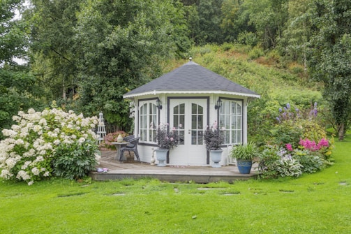 a white gazebo surrounded by flowers and greenery