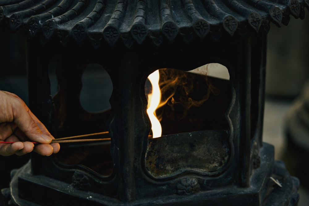 a person holding a stick in front of a stove