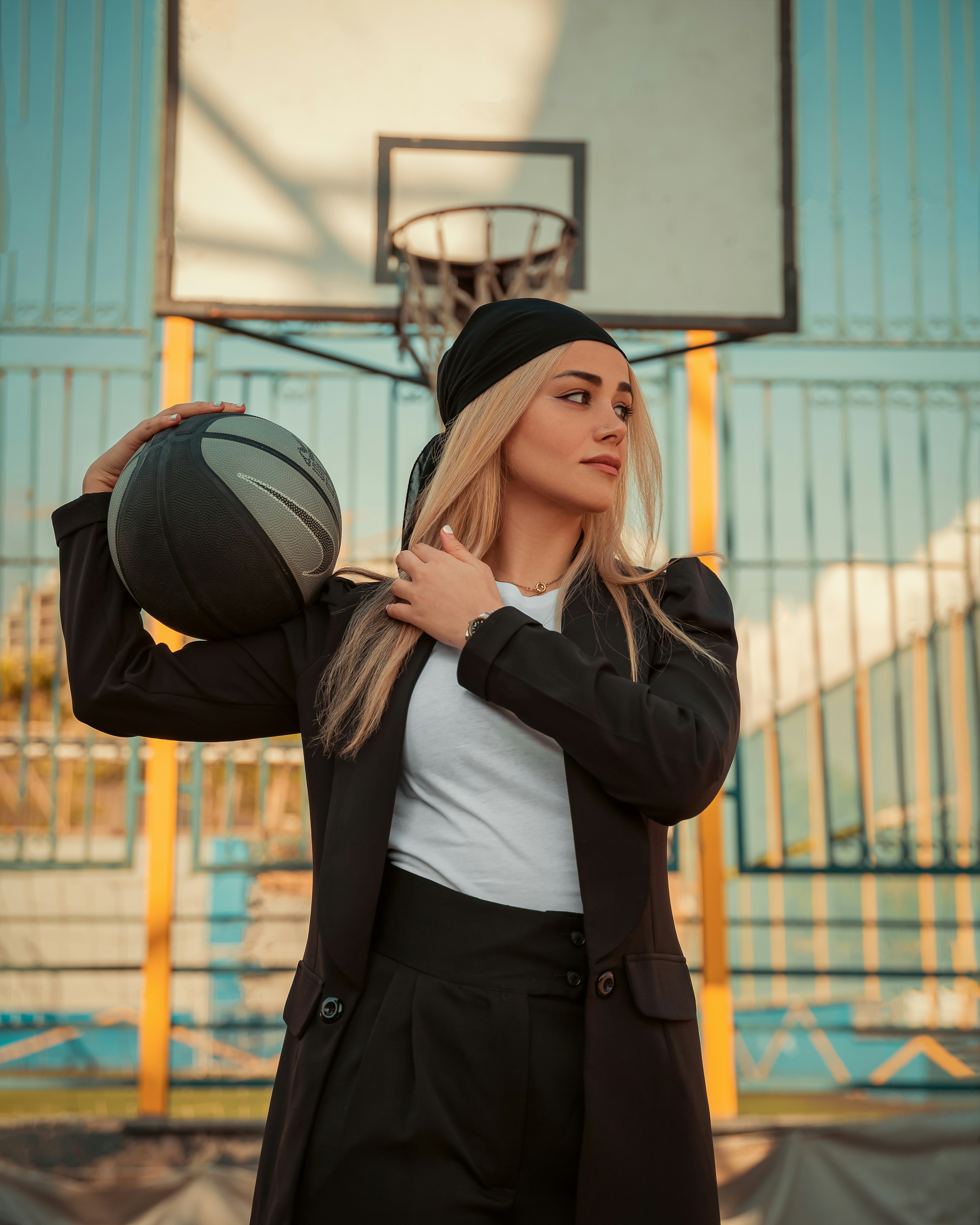 a woman holding a basketball in front of a basketball hoop