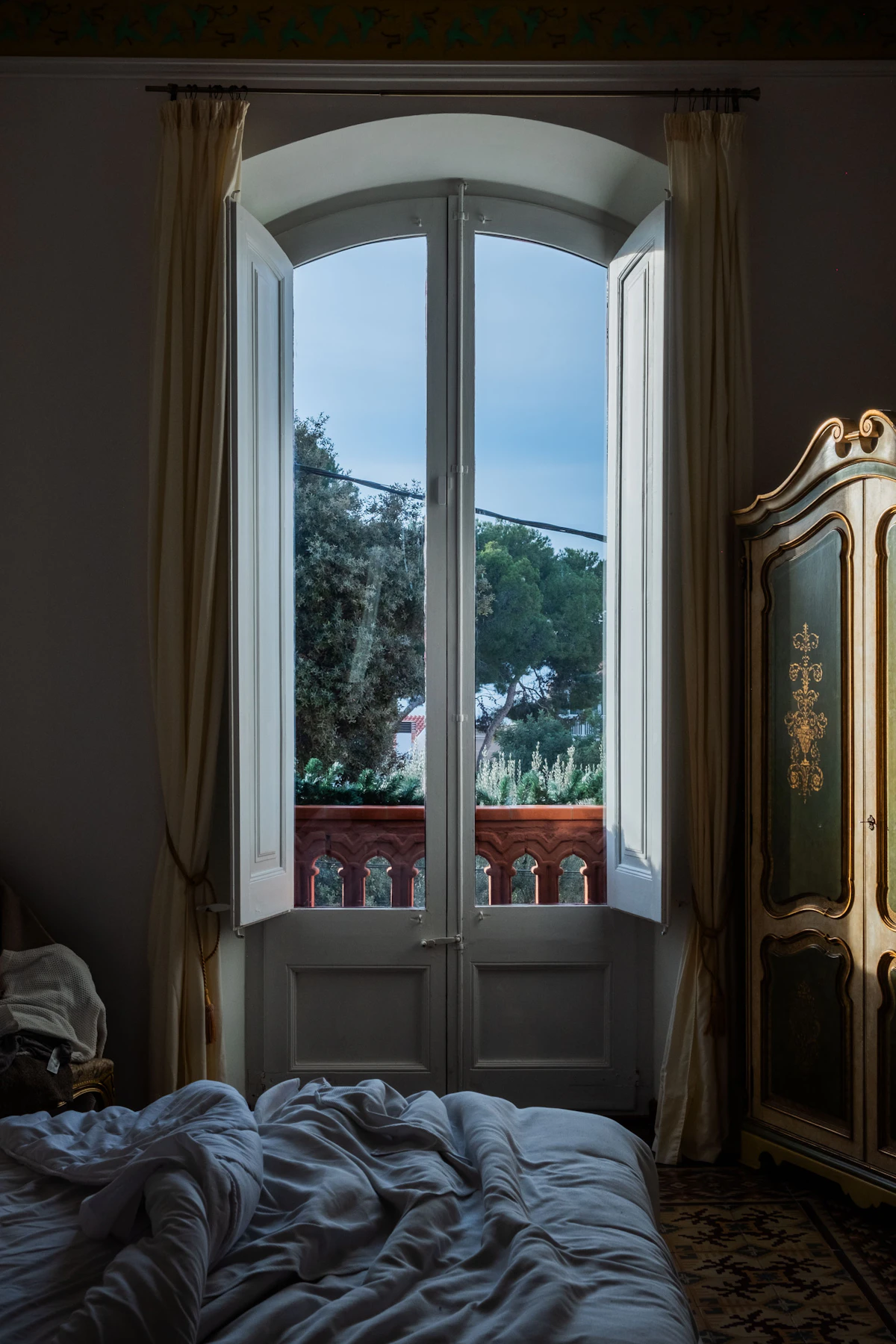 Quarto sóbrio de hotel com cortinas e estores junto à janela