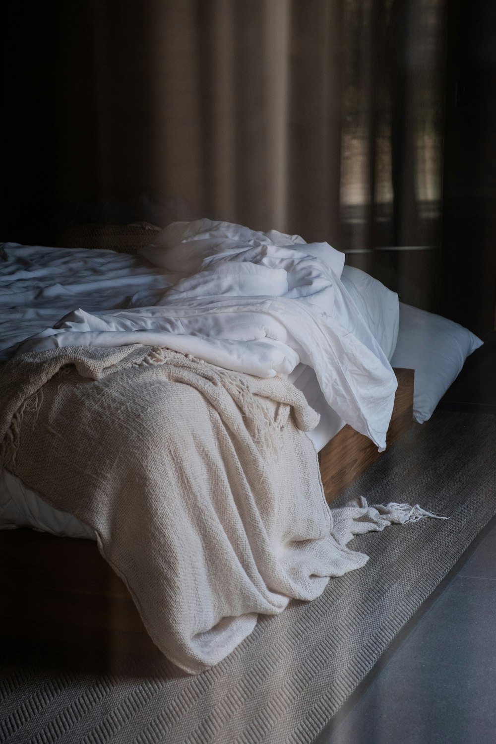 an unmade bed with a white blanket on top of it