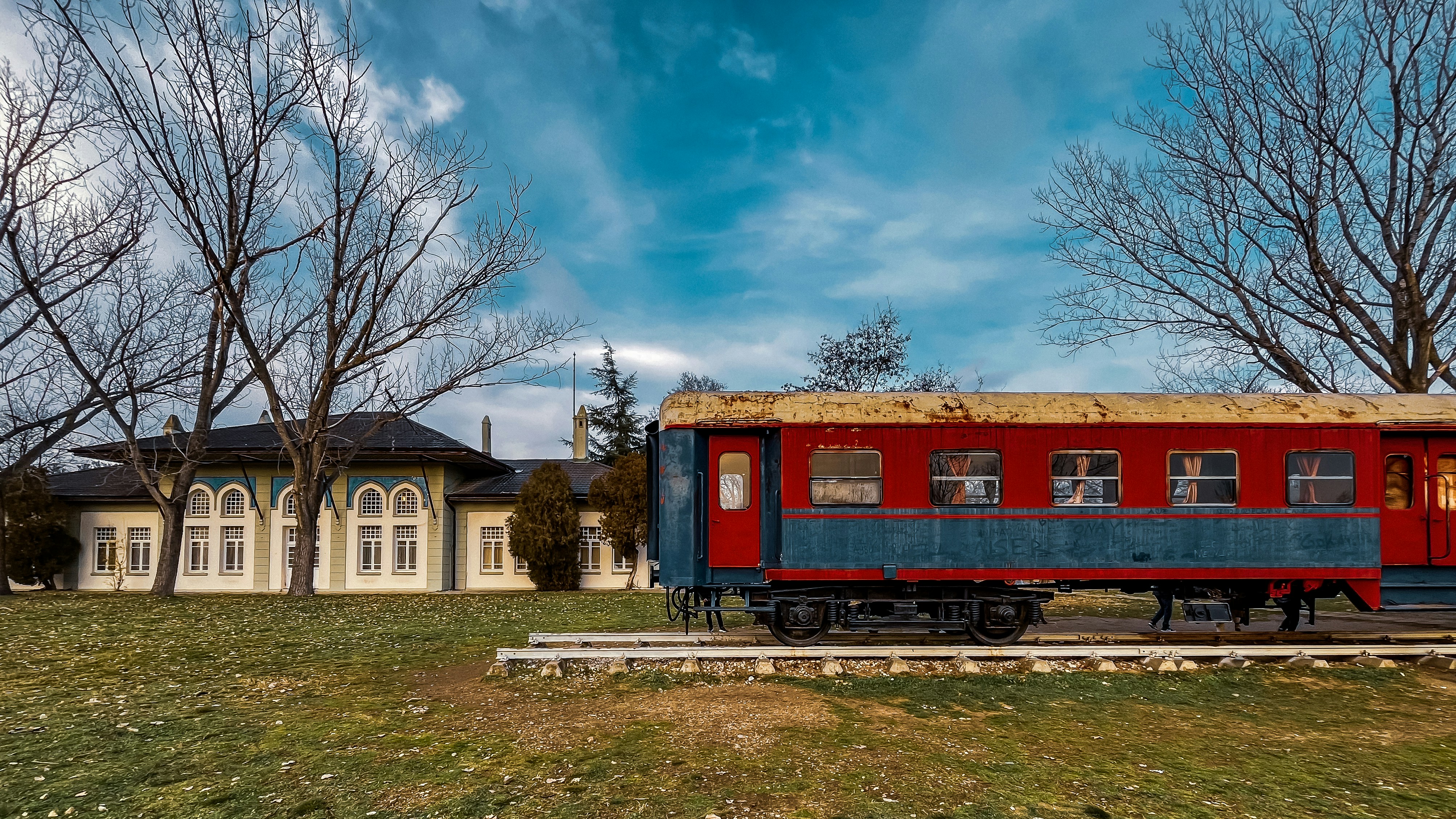 a red and blue train car sitting in a field