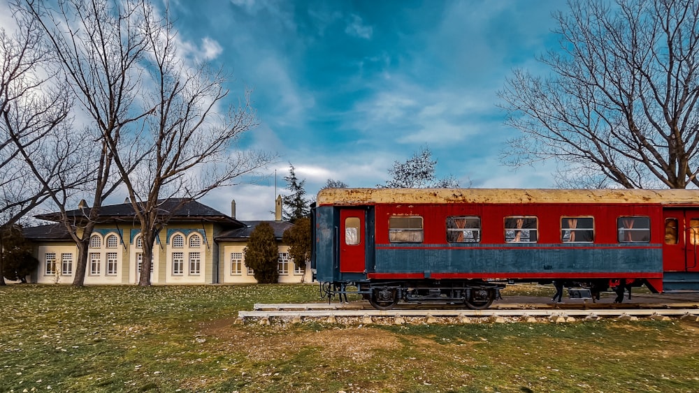 a red and blue train car sitting in a field