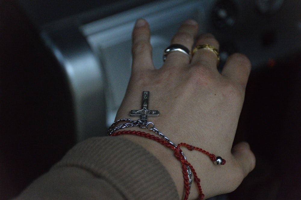 a person wearing bracelets and a cross on their wrist