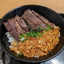 a black bowl filled with meat and rice