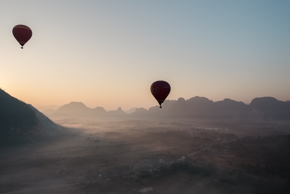 a group of hot air balloons flying over a valley