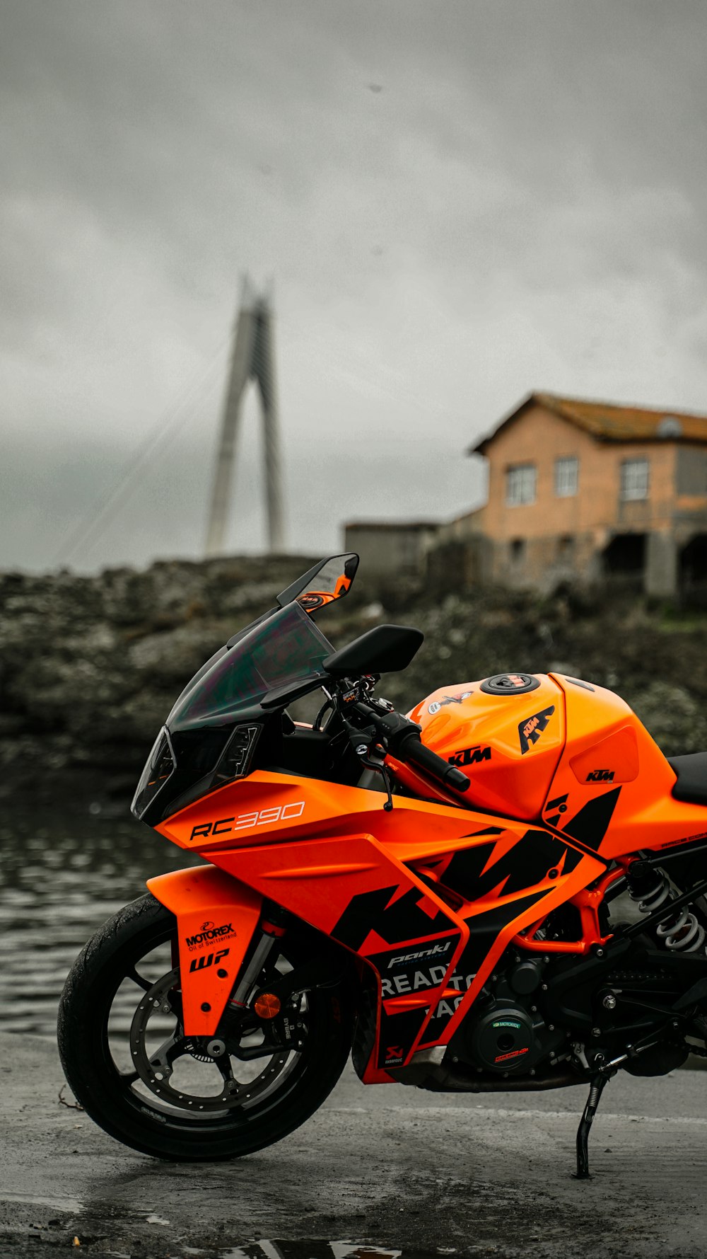 ein orangefarbenes Motorrad, das vor einem Gewässer geparkt ist