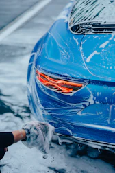 a person washing a blue car with a rag