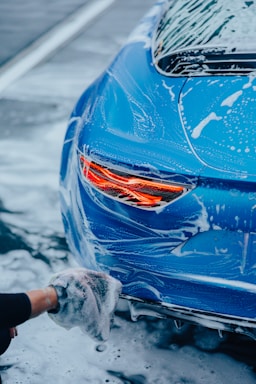 a person washing a blue car with a rag