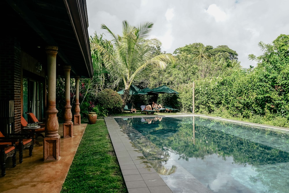 a long pool with chairs and an umbrella next to it