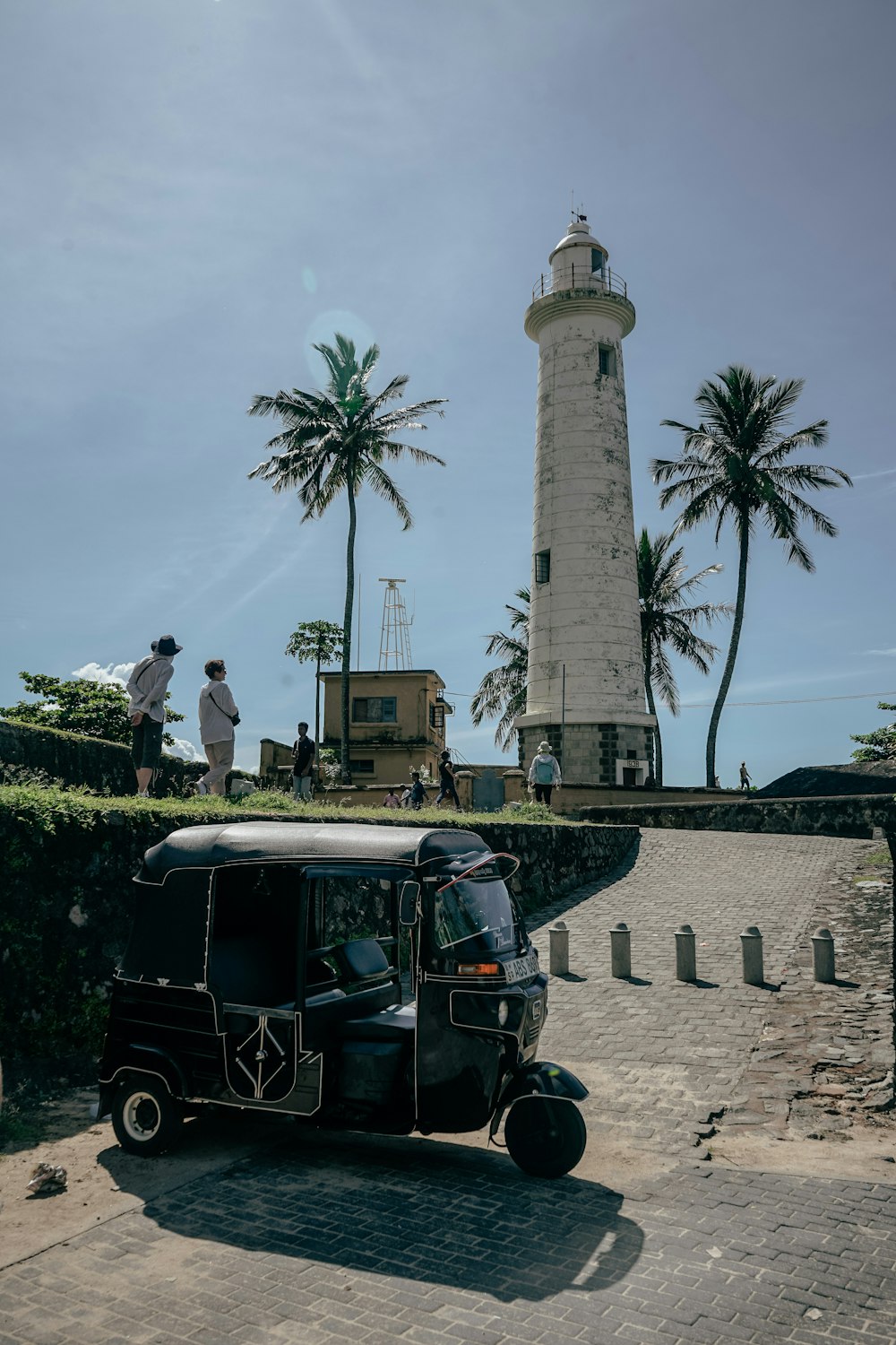 a tuk tuk parked in front of a lighthouse