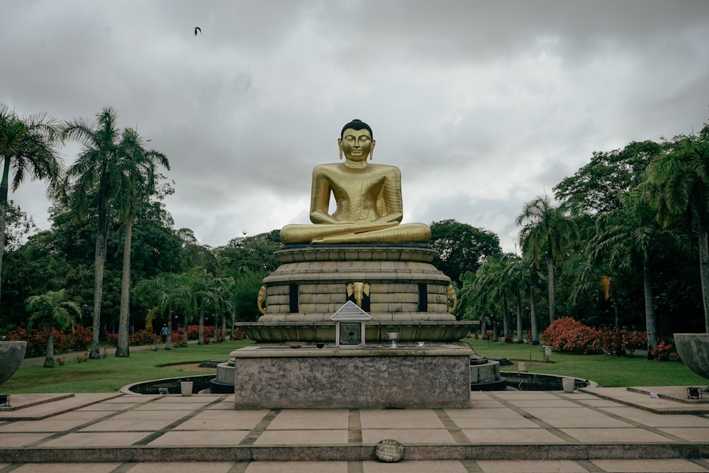 a large golden buddha statue sitting in a park