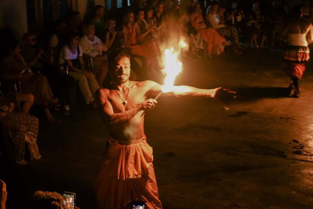 a man holding a fire stick in front of a crowd