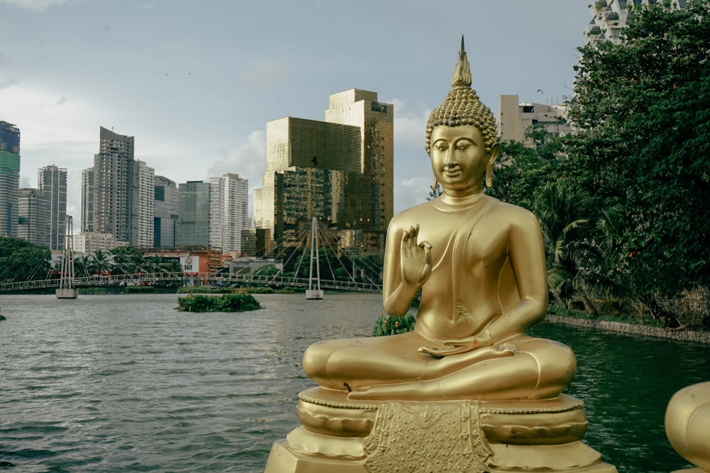 a golden buddha statue sitting in front of a body of water