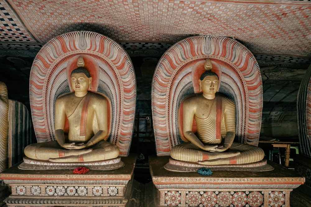 two statues of buddhas sitting in a room